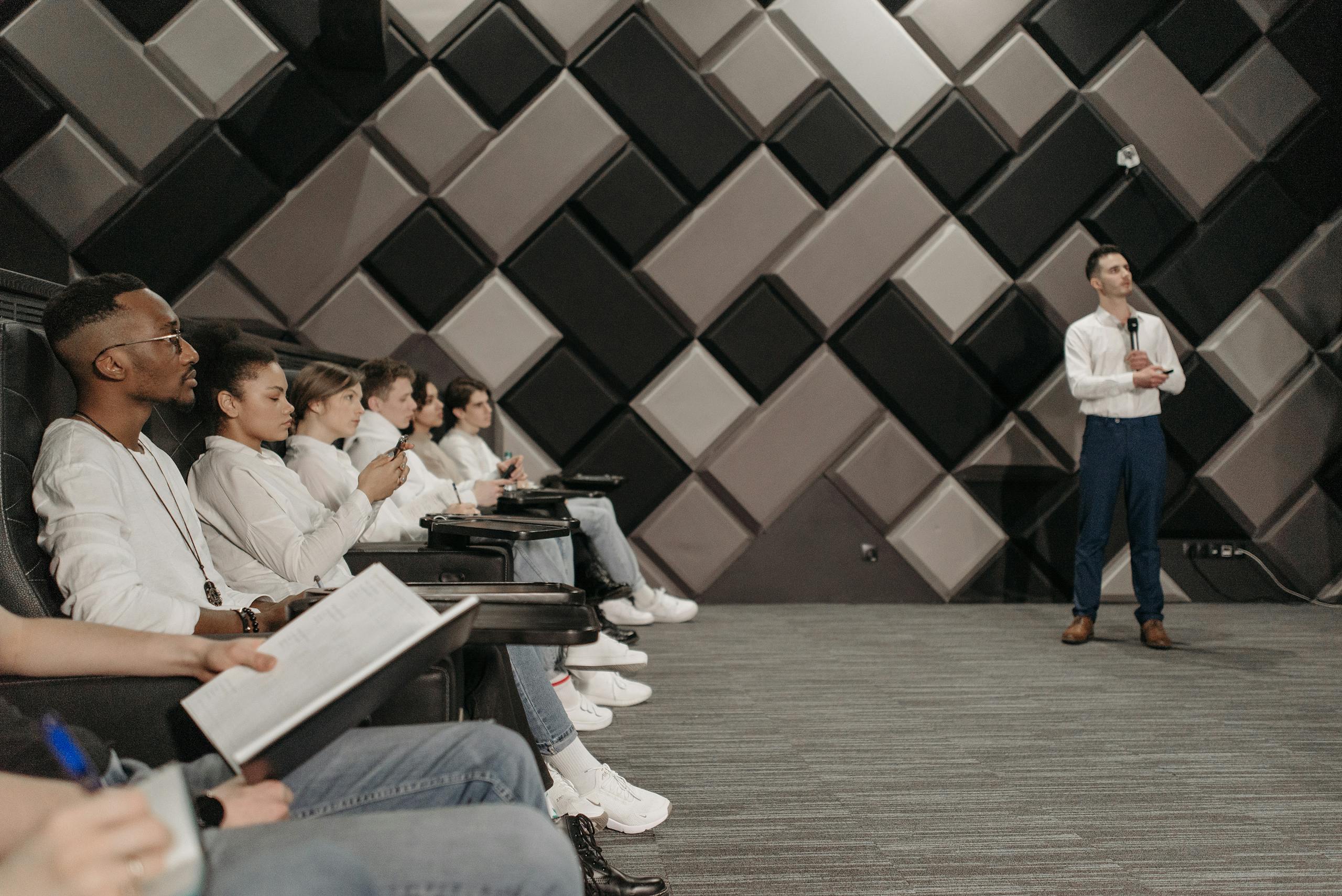 Diverse group of professionals attending a seminar indoors, listening intently to a presenter.